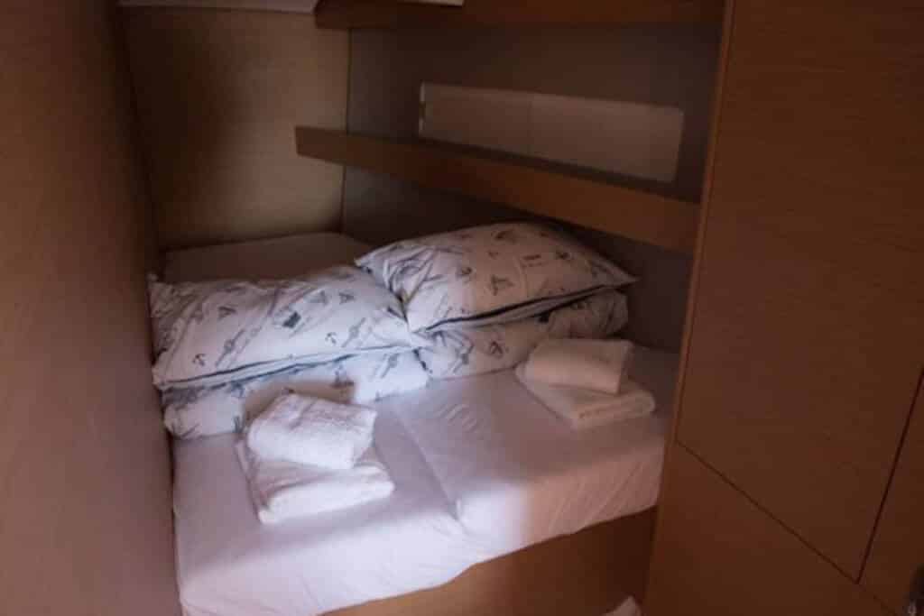 Ein kleines, enges provisorisches Schlafzimmer mit weißen Laken und Handtüchern in einem Pappkarton verkörpert das Konzept minimalistischer und improvisierter Lebensbedingungen, ähnlich denen auf einem Segeltörn.