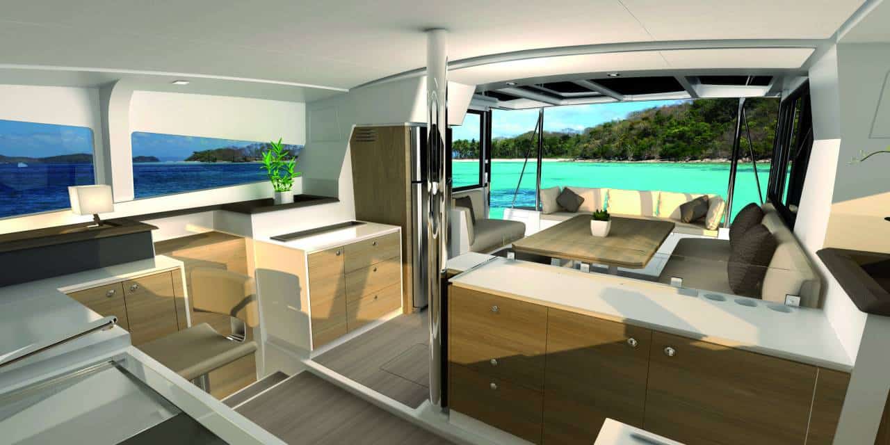 Innenansicht einer modernen Segelyacht mit einem geräumigen Wohnbereich mit Sofas, einem Essbereich und einer Küche, alles mit Blick durch große Fenster auf einen malerischen tropischen Strand.