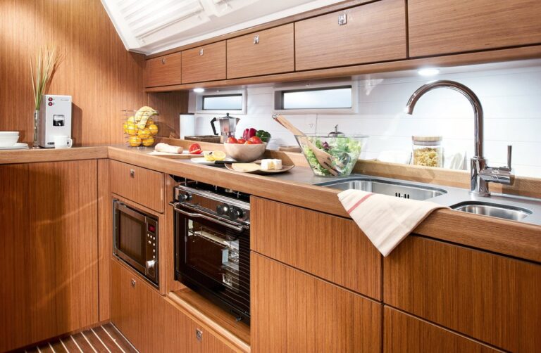 Eine moderne Küche mit eleganten Holzschränken und Geräten aus Edelstahl, darunter ein eingebauter Ofen und eine Spüle. Die Theke ist mit frischem Obst und Gemüse geschmückt.