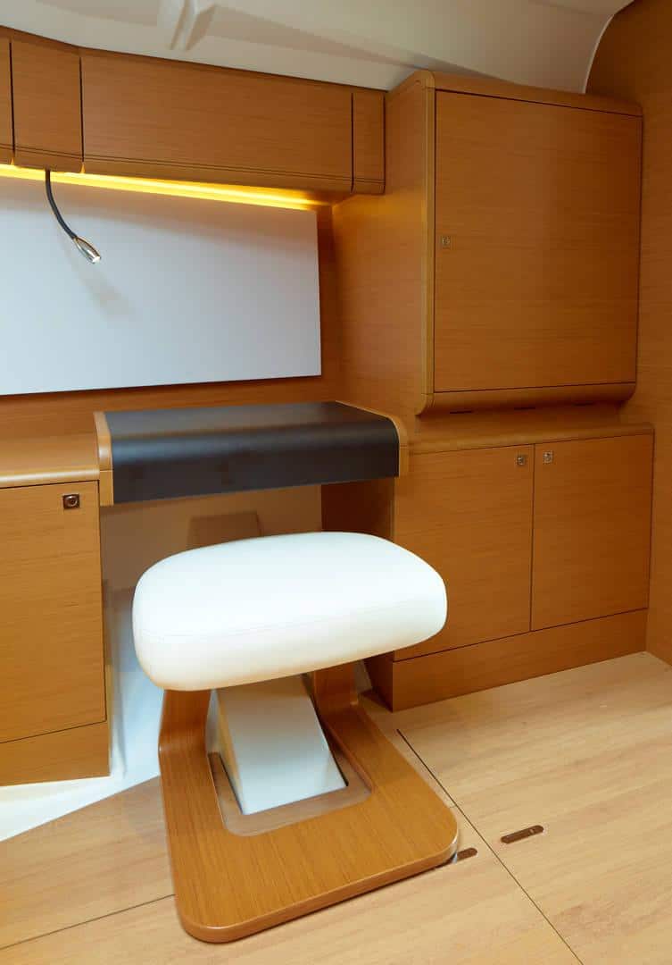 Modernes, minimalistisches Home-Office mit eleganten Holzmöbeln, integrierter Beleuchtung und einem modernen weißen Schreibtischstuhl. Das Design zeichnet sich durch klare Linien und effiziente Raumausnutzung aus, ideal für die Planung Ihres nächsten Segelurlaubs.