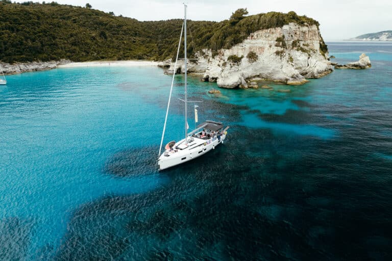 Segelboot auf blauem Wasser im Sommer mit grünen Klippen im Hintergrund gibt sommerliche Atmosphäre