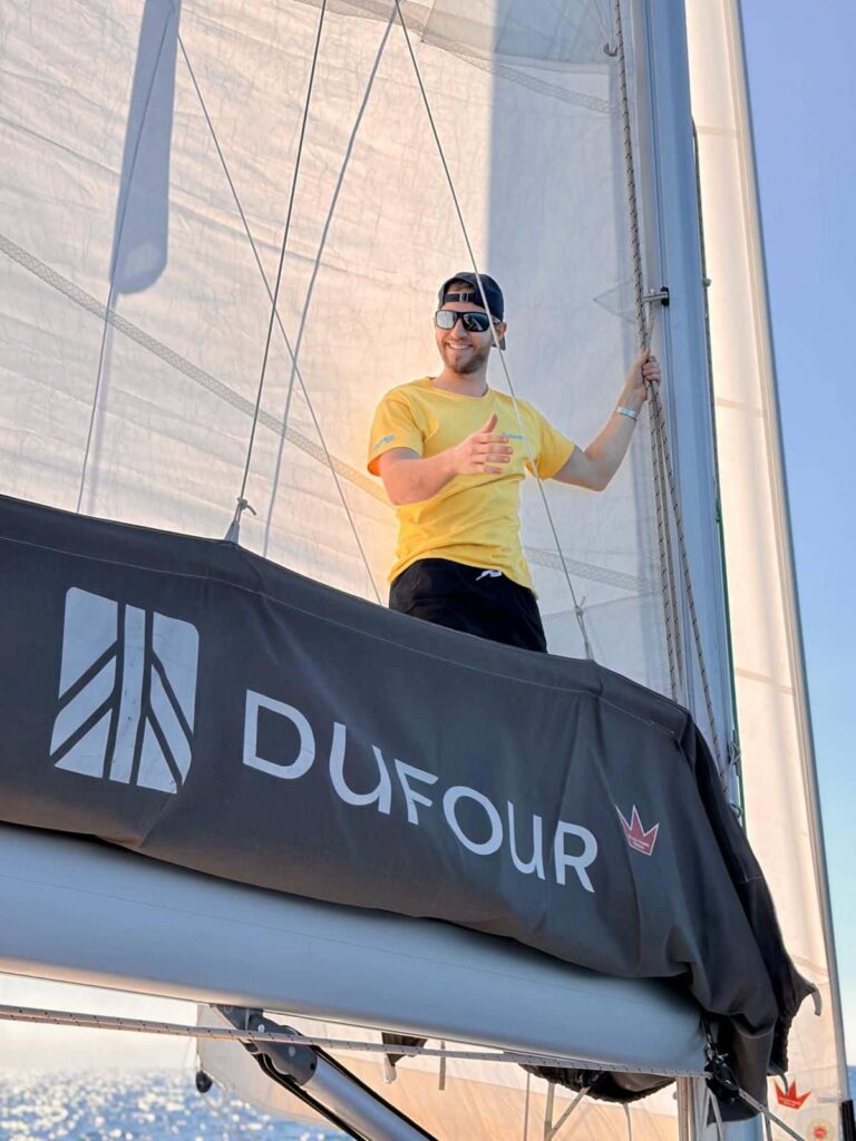 Skipper Friedi steuert ein Segelboot im Sailwithus-T-Shirt