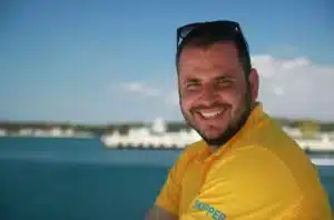 Skipper Jürgen steuert ein Segelboot im Sailwithus-T-Shirt