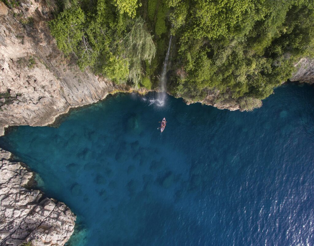 Discover the serene beauty of Fethiye's lagoon with a kayak navigating through azure waters surrounded by lush cliffs.