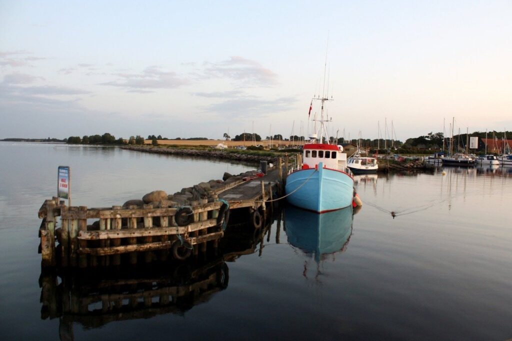 Ruhiger kleiner Fischerhafen mit blauem Holzkutter an der Ostsee – segeln ostsee mit sailwithus