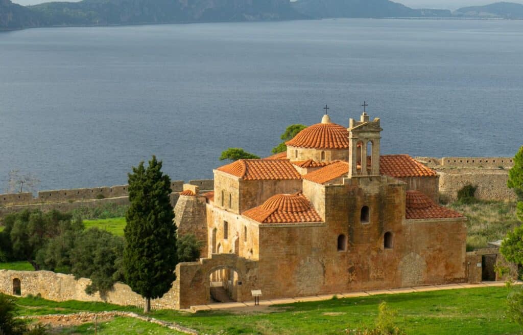A serene view of a historic stone church near the sea in Pylos, Greece. segeln peloponnes 7-tage-törnvorschlag