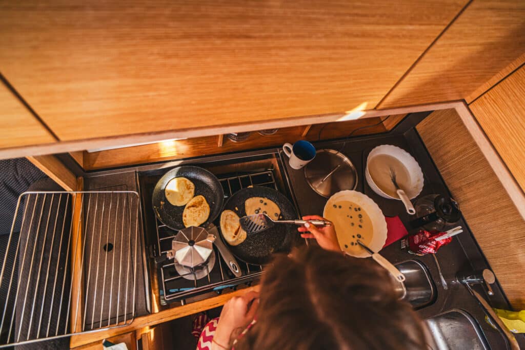 A crew member cooking breakfast in the galley of a sailing yacht
