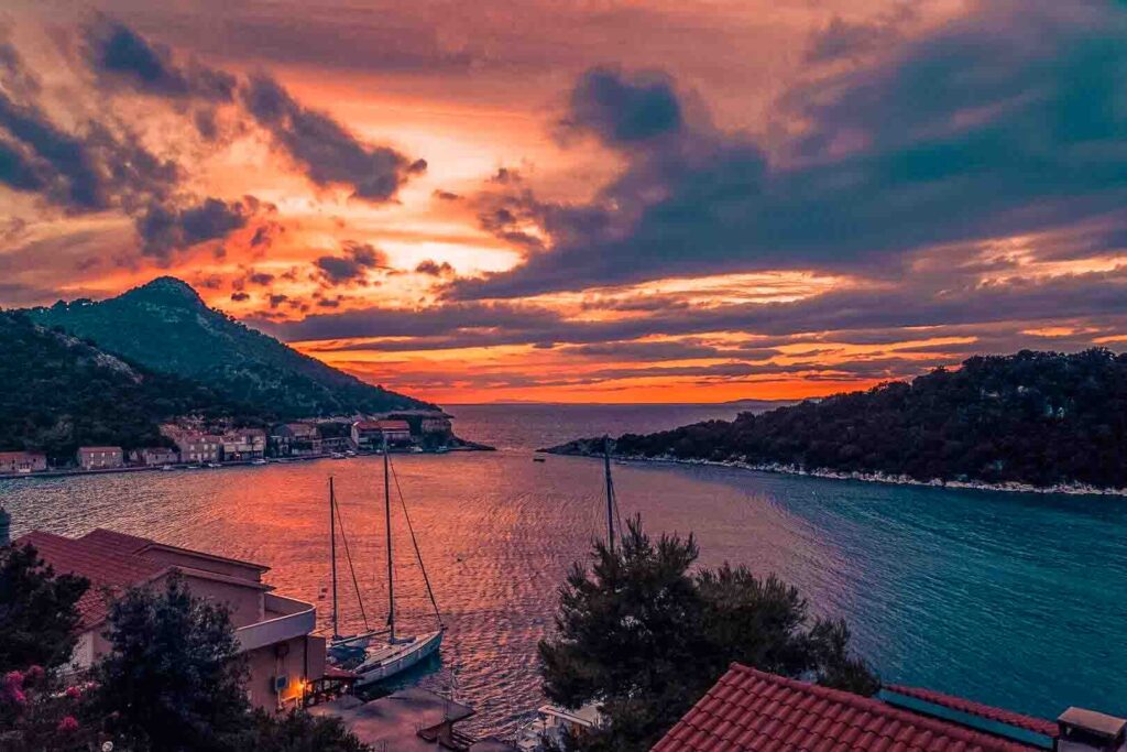 Feuriger Sonnenuntergang mit Segelyachten im Hafen einer kroatischen Küstenstadt – segeln kroatien sailwithus