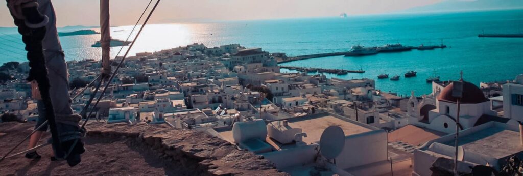 Panoramablick vom Segelschiff auf Mykonos Stadt mit weißen Häusern und Hafen bei Sonnenuntergang – segeln griechenland sailwithus