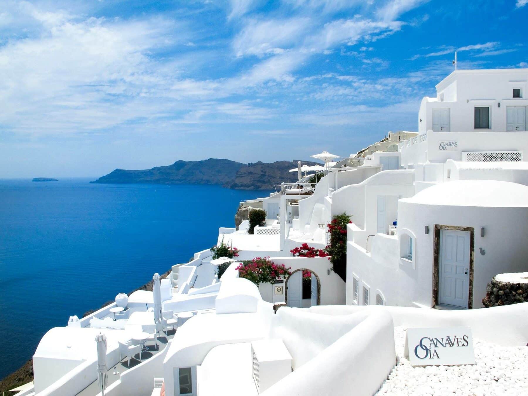A Greek island bay with clear turquoise water and whitewashed houses on the hillside