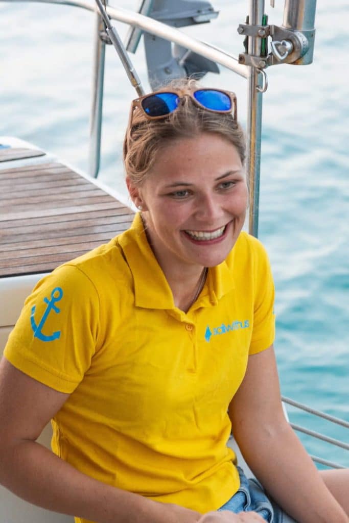 Skipperin Lea steuert ein Segelboot im Sailwithus-T-Shirt